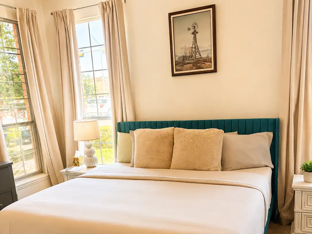 Bed in front of windows with a night table and lamp